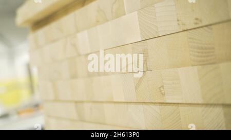 Nahaufnahme der Holzwandstruktur mit Quadraten. Aktion. Helle Stapel von quadratischen Holzwürfeln, die eine Wand bilden. Holzbeschichtungsmuster. Stockfoto