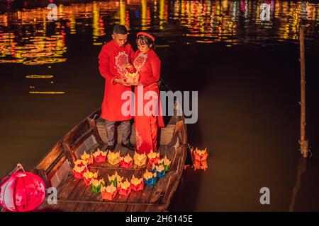 Hoi an, Vietnam, 27.12.2020: Glückliche Paare fahren auf einem Nationalboot auf dem Hintergrund der alten Stadt Hoi, Vietnam. Vietnam öffnet sich für Touristen Stockfoto