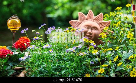 Blumen mit Ton-Sonnendekor auf dem Balkon. Oase in der Stadt. Stockfoto