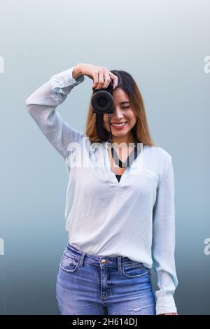 Porträt des Fotografen lächelnd, während Foto mit professioneller Kamera, schöne Brünette Frau. Hobby-Konzept Stockfoto
