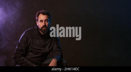 Großer Kopierraum im Panorama eines Mannes in einer Aufnahmestidia mit Rauch und farbigen Lichtern Stockfoto