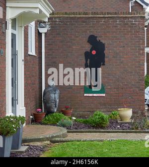 Figur eines zweidimensionalen Soldaten mit einem roten Mohn und der Botschaft, dass wir es nicht vergessen, an einer Wand eines Privathauses. Stockfoto