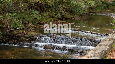 Dieser kleine Wasserfall in einem Park am Straßenrand in Arkansas ist ruhig und friedlich. Bokeh-Effekt. Stockfoto
