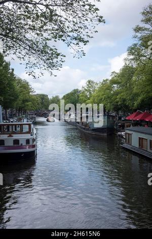 Hausboote liegen an einem Kanal im Zentrum von Amsterdam, Niederlande. Da 50 % der Niederlande unter dem Meeresspiegel liegen, ist sie unglaublich anfällig für den durch den Klimawandel angetriebenen Anstieg des Meeresspiegels. Sie schränkt auch die Menge an bewohnbarem Platz für Menschen ein und es müssen alternative Lösungen gefunden werden. Stockfoto