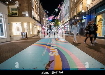 LONDON - 1. NOVEMBER 2021: Farbenfroher Tisch mit Weihnachtslichtern der Carnaby Street im Hintergrund Stockfoto