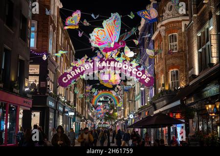 LONDON - 1. NOVEMBER 2021: Eine geschäftige Carnaby Street mit den farbenfrohen Weihnachtsdekorationen, die oben hängen Stockfoto