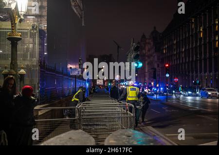 LONDON - 1. NOVEMBER 2021: Polizeibeamte stehen nachts neben temporären Metallzäunen vor den Houses of Parliament Stockfoto
