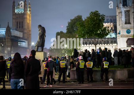 LONDON - 1. NOVEMBER 2021: Die Polizei beschützt die Statue von Winston Churchill auf dem Parliament Square während des Million Mask March Stockfoto