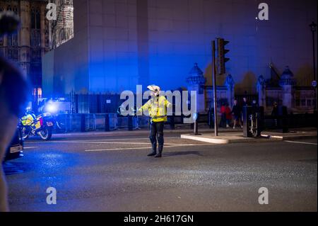 LONDON - 1. NOVEMBER 2021: Ein Polizeimotorradfahrer lenkt den Verkehr vor den Houses of Parliament während des Millionenmaskenmarsches Stockfoto