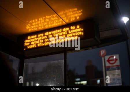 LONDON - 1. NOVEMBER 2021: Beleuchtetes Schild an einer Bushaltestelle, das vor einer Unterbrechung des Busdienstes aufgrund von Demonstrationen warnt Stockfoto