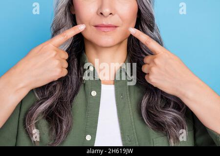 Zugeschnittenes Foto von niedlichen älteren weißen Frisur Dame Index Mund tragen Khaki Shirt isoliert auf blauem Hintergrund Stockfoto