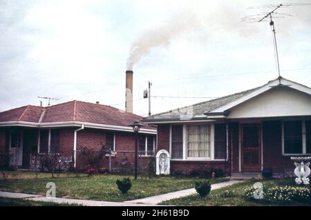 Der Rauch des Kaiser Aluminium Werks im Hintergrund verteilt die Dämpfe über das große Wohngebiet im Chalmette-Abschnitt von New Orleans Ca. März 1973 Stockfoto