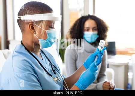 Ärztin in schützender Gesichtsmaske Füll Spritze mit Impfstoff in der Klinik während covid-19 Stockfoto