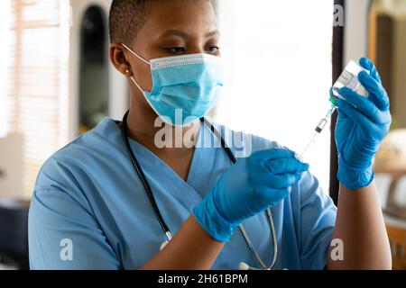 Ärztin in einer schützenden Gesichtsmaske, die während der Covid-19-Krise eine Spritze mit Impfstoff in der Klinik enthält Stockfoto