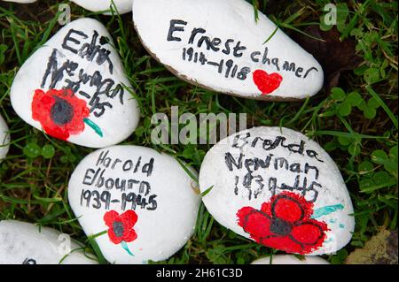 Ley Hill, Chestham, Großbritannien. November 2021. Anlässlich des Gedenktages und des Gedenksonntages wurde eine wunderschöne Mohnkaskade aus gestrickten Mohnblumen am Beacon auf dem Common in Ley Hill, Chestham, ausgestellt. Schulkinder haben auch Gedenksteine mit den Namen der Dorfbewohner gemalt, die in den beiden großen Kriegen getötet wurden. Die Steine wurden herzförmig vor einem Gedenkkreuz gelegt. Quelle: Maureen McLean/Alamy Live News Stockfoto