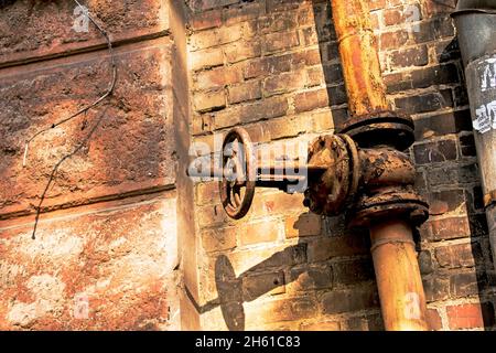 Altes rostetes Gasregelventil an der Wand. Ein Industrieventil in einem großen System. Das Gasübertragungssystem der Ukraine ist ausgefallen. Stockfoto