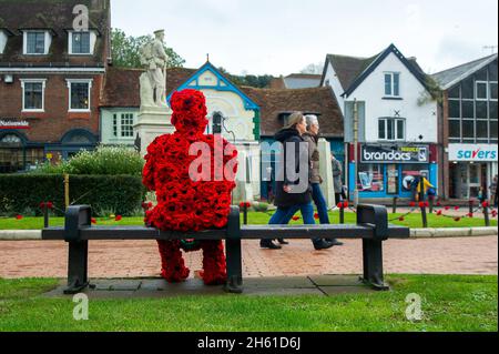 Chensham, Großbritannien. November 2021. Anlässlich des Gedenktages und des Erinnerungssonntags wurde ein Mohnmann aus gestrickten Mohnblumen mit einer weißen Taube auf einer Bank in der Nähe des war Memorial im Stadtzentrum von Chesham aufgestellt.Quelle: Maureen McLean/Alamy Live News Stockfoto