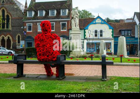 Chensham, Großbritannien. November 2021. Anlässlich des Gedenktages und des Erinnerungssonntags wurde ein Mohnmann aus gestrickten Mohnblumen mit einer weißen Taube auf einer Bank in der Nähe des war Memorial im Stadtzentrum von Chesham aufgestellt.Quelle: Maureen McLean/Alamy Live News Stockfoto