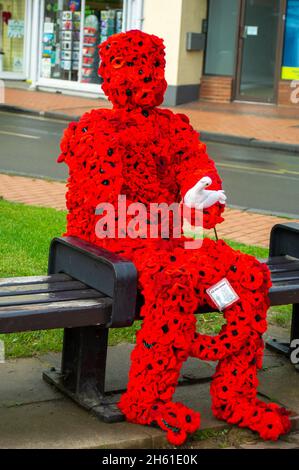 Chensham, Großbritannien. November 2021. Anlässlich des Gedenktages und des Erinnerungssonntags wurde ein Mohnmann aus gestrickten Mohnblumen mit einer weißen Taube auf einer Bank in der Nähe des war Memorial im Stadtzentrum von Chesham aufgestellt.Quelle: Maureen McLean/Alamy Live News Stockfoto