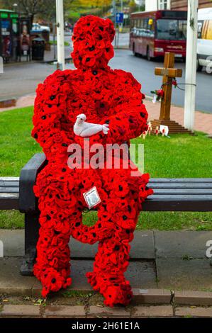 Chensham, Großbritannien. November 2021. Anlässlich des Gedenktages und des Erinnerungssonntags wurde ein Mohnmann aus gestrickten Mohnblumen mit einer weißen Taube auf einer Bank in der Nähe des war Memorial im Stadtzentrum von Chesham aufgestellt.Quelle: Maureen McLean/Alamy Live News Stockfoto