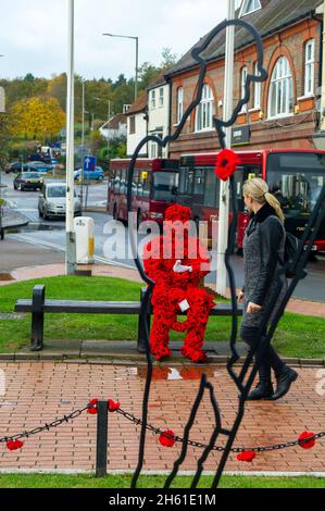 Chensham, Großbritannien. November 2021. Anlässlich des Gedenktages und des Erinnerungssonntags wurde ein Mohnmann aus gestrickten Mohnblumen mit einer weißen Taube auf einer Bank in der Nähe des war Memorial im Stadtzentrum von Chesham aufgestellt.Quelle: Maureen McLean/Alamy Live News Stockfoto