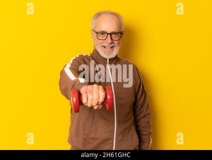 Glücklich reifen Sport Mann hält Hantel isoliert über gelben Hintergrund. Stockfoto