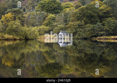 Blick über die ruhige aussicht auf das alte Bootshaus, das sich am Ufer des Rydal Water im Lake District befindet, Herbst gleich um die Ecke. Stockfoto