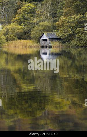 Blick über die ruhige aussicht auf das alte Bootshaus, das sich am Ufer des Rydal Water im Lake District befindet, Herbst gleich um die Ecke. Stockfoto