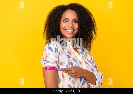 Foto von optimistischen jungen welligen Frisur Dame Index Arm tragen weiße Bluse auf gelbem Hintergrund isoliert Stockfoto