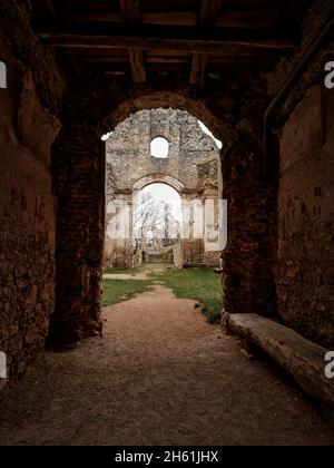 Blick durch einen dunklen Steinbogen in Katarinka, die Kirche und das Katharinenkloster in der Nähe von Dechtice, Slowakei. Stockfoto