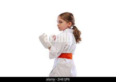 Ein kleines Mädchen, junges Karate im Kimono, das isoliert auf weißem Hintergrund praktiziert. Konzept von Sport, Bildung, Fähigkeiten Stockfoto