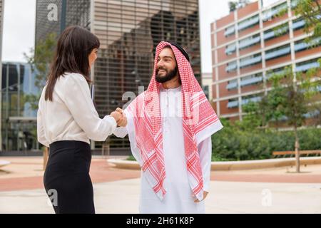 Glücklich lächelnder arabischer Mann Klient und kaukasische Geschäftsfrau schüttelt die Hände, fühlt sich zufrieden nach Verhandlungen, grüßt sich im Freien, multikulturelle Geschäftsleute beenden Treffen Stockfoto