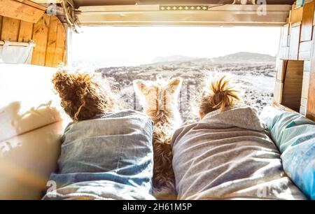 Hipster-Paar mit niedlichem Hund, der zusammen auf einem Oldtimer-Transporter reist - Life inspiration Concept mit Hippie-Leuten auf einem Minivan-Abenteuerausflug Stockfoto