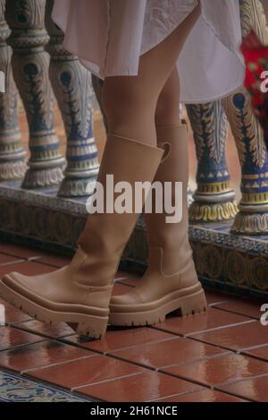 Nahaufnahme unkenntlich Mädchen trägt beige regen Stiefel, Herbst-Winter 2021 Mode-Outfit an einem regnerischen Tag im Freien. Stockfoto