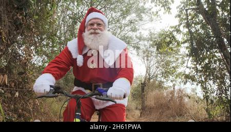 Der Weihnachtsmann fährt mit dem Fahrrad auf unbefestigten Straßen. Stockfoto