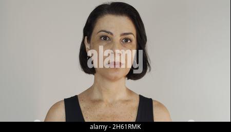 Attraktive Frau mittleren Alters mit schönen ernst an der gelben Wand. Ziemlich ältere Frau, erfolgreiches Vertrauen. Stockfoto