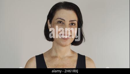 Attraktive Frau mittleren Alters mit einem schönen Lächeln auf der gelben Wand. Ziemlich ältere Frau, erfolgreiches Vertrauen. Stockfoto