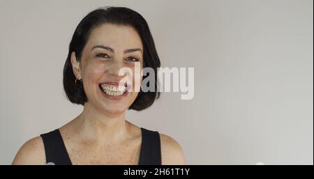 Attraktive Frau mittleren Alters mit einem schönen Lächeln auf der gelben Wand. Ziemlich ältere Frau, erfolgreiches Vertrauen. Stockfoto