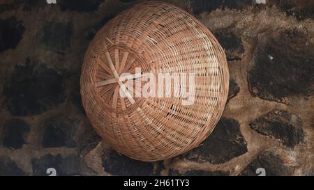 Der Korb aus handgestricktem Bambus wird an die Wand gehängt Stockfoto