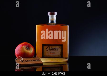 Prag, Tschechische Republik - 26. Oktober 2021: Glas Calvados Brandy und roter Apfel auf dem Glastisch. Calvados ist ein Apfelbrand mit Appellation d Or Stockfoto