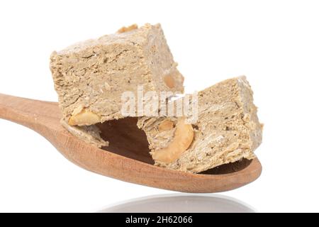 Zwei Halva-Stücke mit Erdnüssen mit Holzlöffel, Nahaufnahme, isoliert auf Weiß. Stockfoto