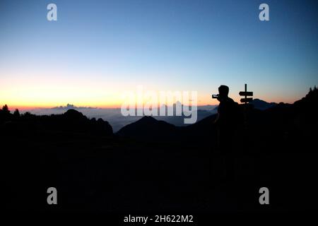 Junger Mann, der mit seinem Handy fotografiert, zum Gipfel der kampenwand (1669 m) in chiemgau, chiemgauer alpen, bei aschau, oberbayern, bayern, süddeutschland, deutschland Stockfoto