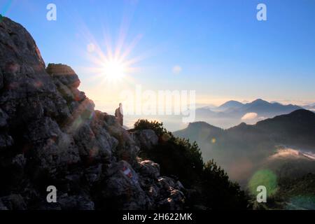 Mann über der Wolkendecke bei einer Wanderung zum Gipfel der kampenwand (1669 m) im chiemgau,Sonne,Rücklicht,chiemgauer alpen,bei aschau,oberbayern,bayern,süddeutschland,deutschland Stockfoto