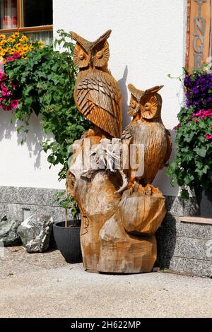 Geschnitzte Eulenfigur auf einem Baumstumpf, Eulen, Eulen, Skulpturen, Holzschnitzereien in navis, Blumen, Haus, Eingang, navistal, wipptal, österreich, tirol Stockfoto