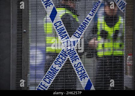 Glasgow, Schottland, Großbritannien. Polizisten stehen neben einer Kassette mit der Aufschrift ‘Climate Crime Scene’, die von Klimaprotesten am Zaun festgebunden worden war, am Sicherheitszaun vor dem Veranstaltungsort der UN-Klimakonferenz COP26, während die Konferenz und die Treffen im Inneren in Glasgow, Schottland, am 12. November 2021, zu einem Finale kommen. Foto: Jeremy Sutton-Hibbert/ Alamy Live News. Stockfoto