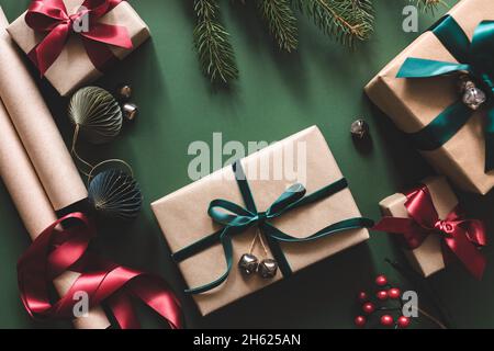 Weihnachts-Wickeltisch mit Geschenkschachteln, Bändern, Papierrollen auf grünem Hintergrund. Stockfoto