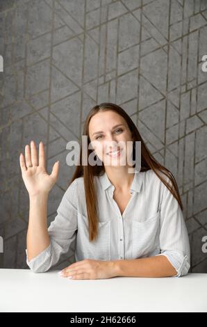 Virtuelles Porträt einer lächelnden Mitarbeiterin während eines Videomeeting, einer fröhlichen jungen kaukasischen Frau, die Hand winkt, die Gesprächspartner online begrüßt, virtuelle Konferenzen Stockfoto
