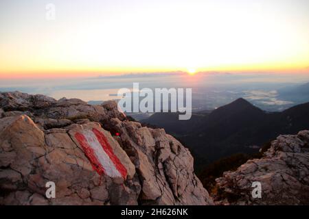 stimmungsvoller Sonnenaufgang, Blick vom Gipfel der kampenwand (1669 m) im chiemgau,Wegmarkierungen auf den Felsen,chiemsee,Blick über das Wolkenmeer,chiemgauer alpen,bei aschau,oberbayern,bayern,süddeutschland,deutschland Stockfoto