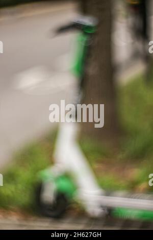 Geparkter Elektroroller am Straßenrand, E-Scooter, abstrakte Unschärfe Stockfoto