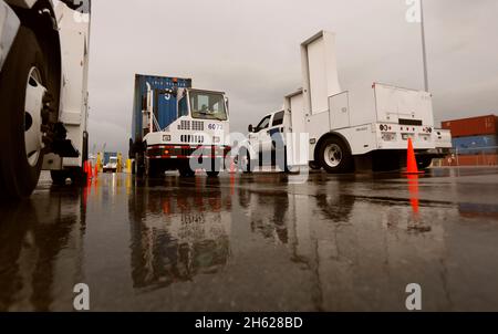 Ein von einem Hafenfahrzeug gezogener Transportcontainer wird von LKW-montierten Strahlungserkennungssystemen gescannt, die von US-Zoll- und Grenzschutzbeamten im Hafen von Miami am 07. Dezember 2015 betrieben werden. Stockfoto